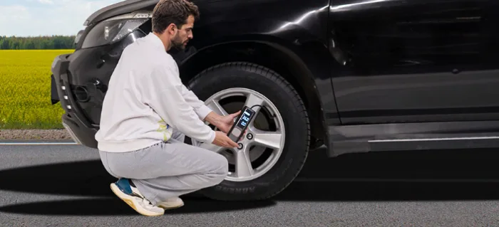 Man checking tire pressure on black SUV