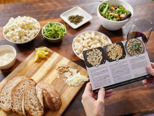 Preparing meal with recipe card and ingredients on table.