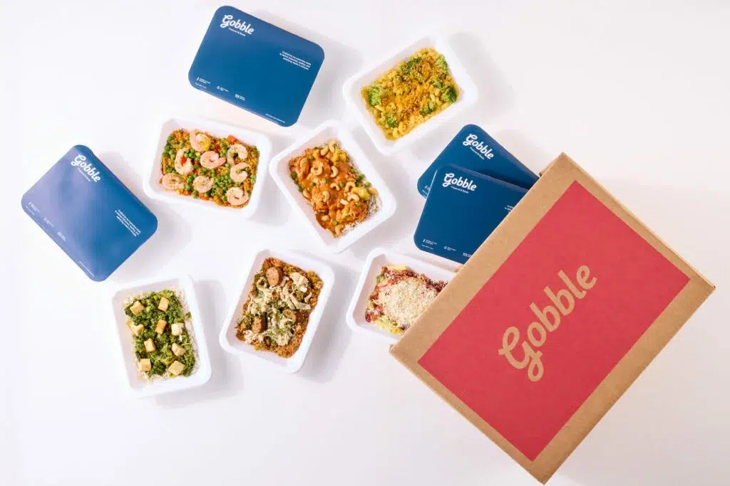 Assorted meal delivery boxes with prepared dishes.