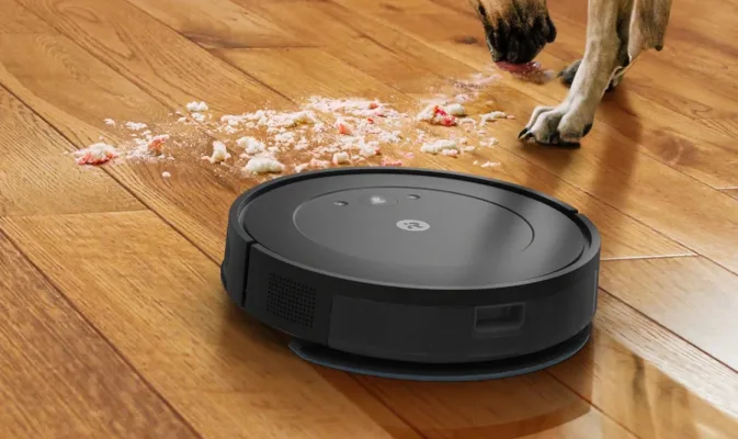 Robot vacuum cleaning crumbs near dog.