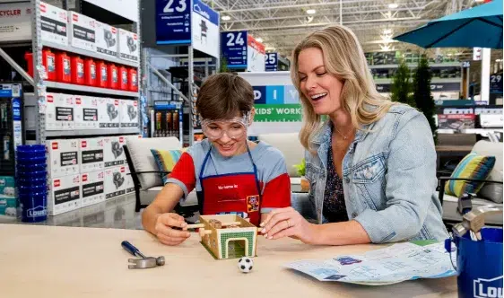 Child building model with adult supervision in store.