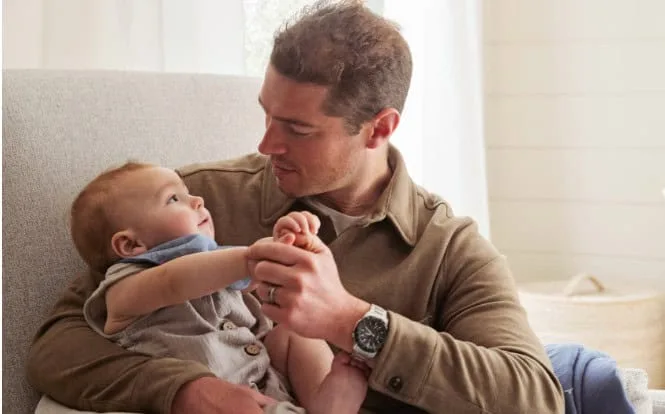Man holding and looking at baby in living room.