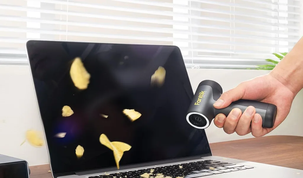 Blowing potato chips off laptop with air blower.