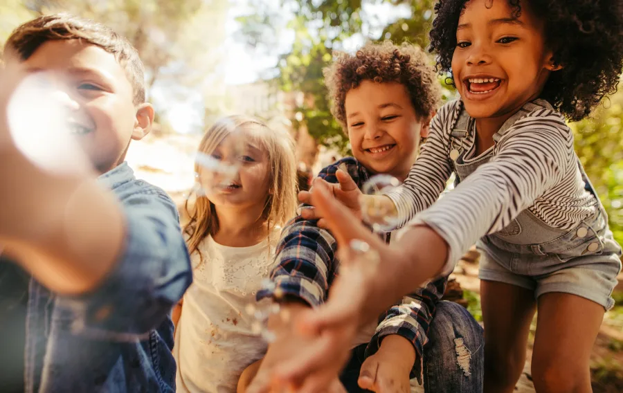 Happy children playing outdoors with bubbles
