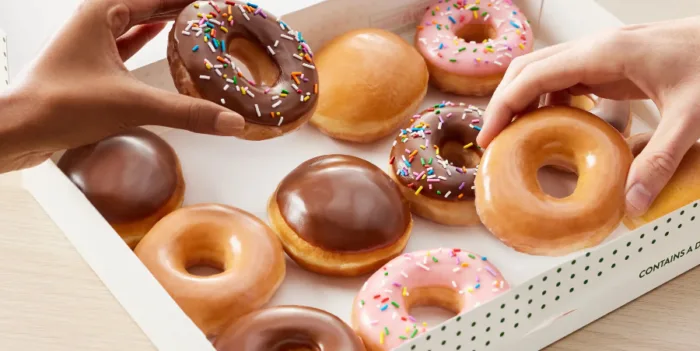 Assorted donuts in a box being picked.