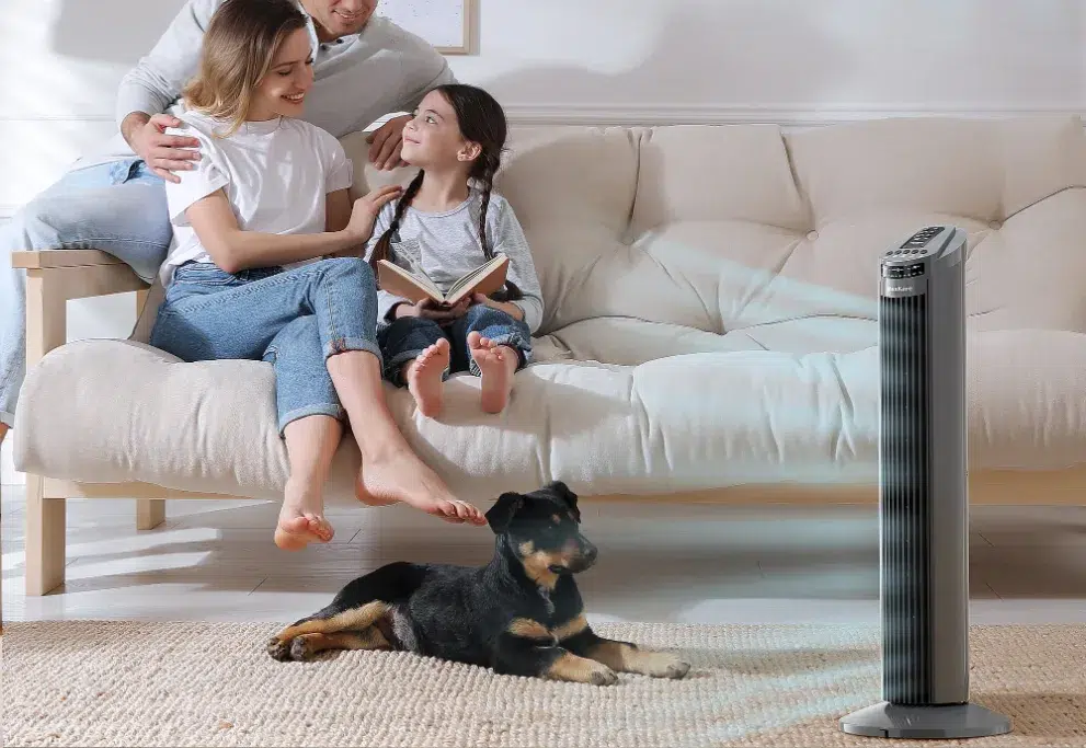 Family relaxing with tower fan and pet dog.