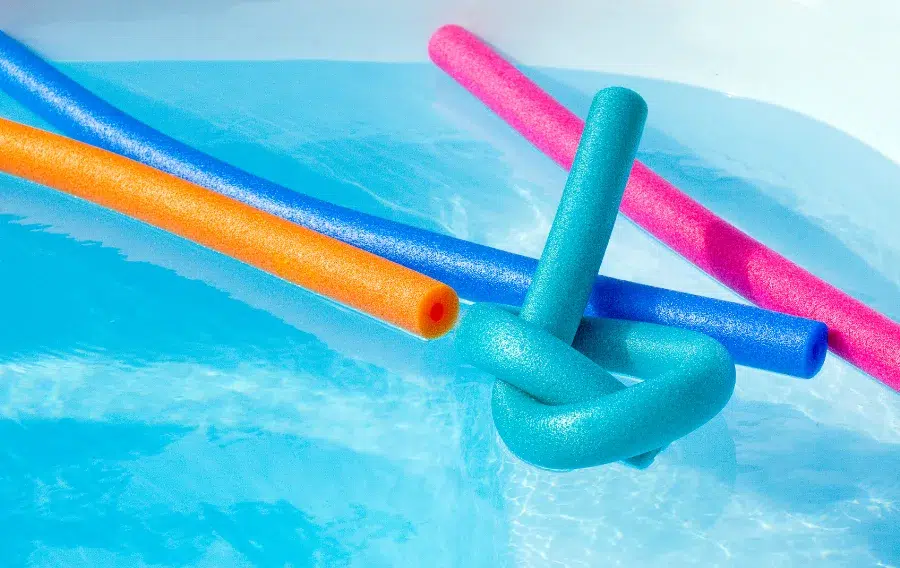 Colorful pool noodles in swimming pool water