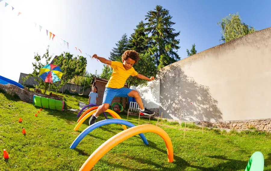 Child jumping over playground obstacle course outdoors.