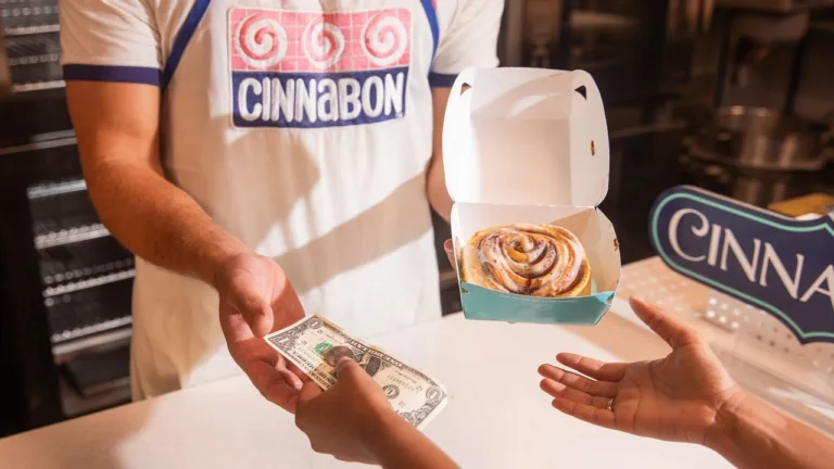 Person buying cinnamon roll at Cinnabon counter.