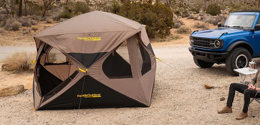 Camping tent set up near blue SUV
