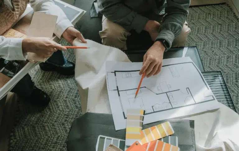 Designers discussing floor plan with color swatches.