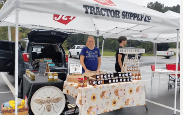 Farmers market booth with honey and preserves display.
