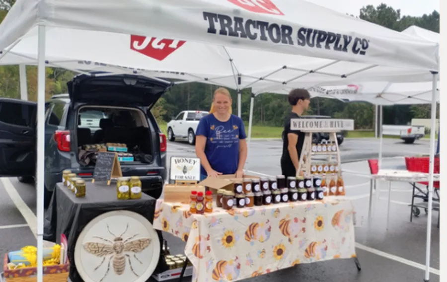 Farmers market booth with honey and preserves display.