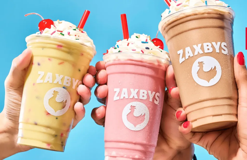 Three colorful milkshakes with whipped cream and sprinkles.