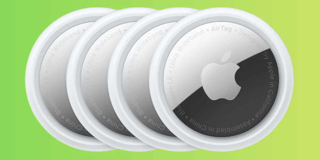 Four Apple AirTags on a green background.