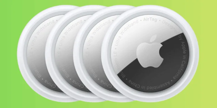 Four Apple AirTags on a green background.
