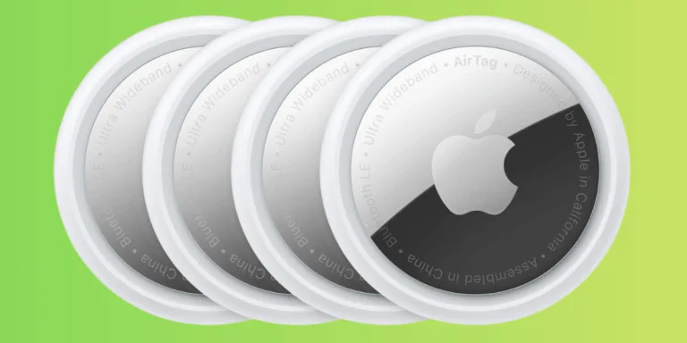 Four Apple AirTags on a green background.