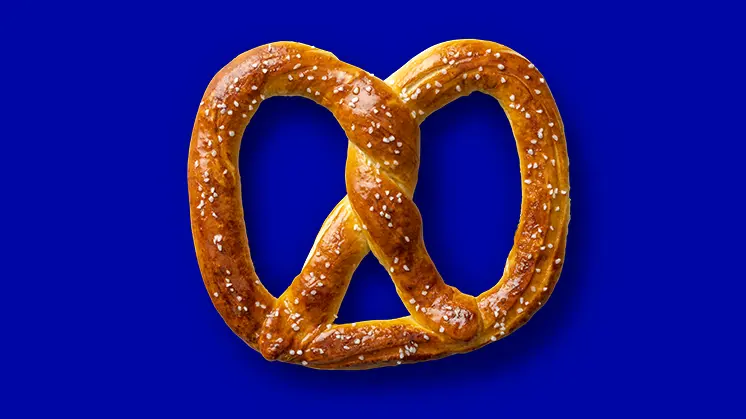 Salted pretzel on blue background.