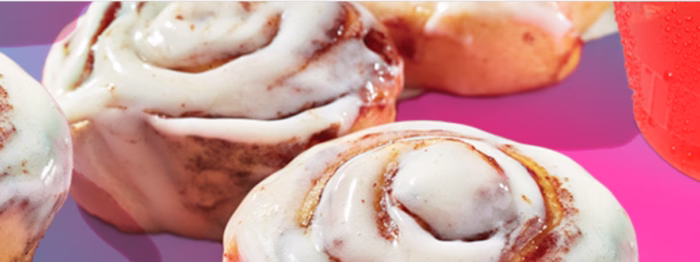 Cinnamon rolls with icing on purple background.