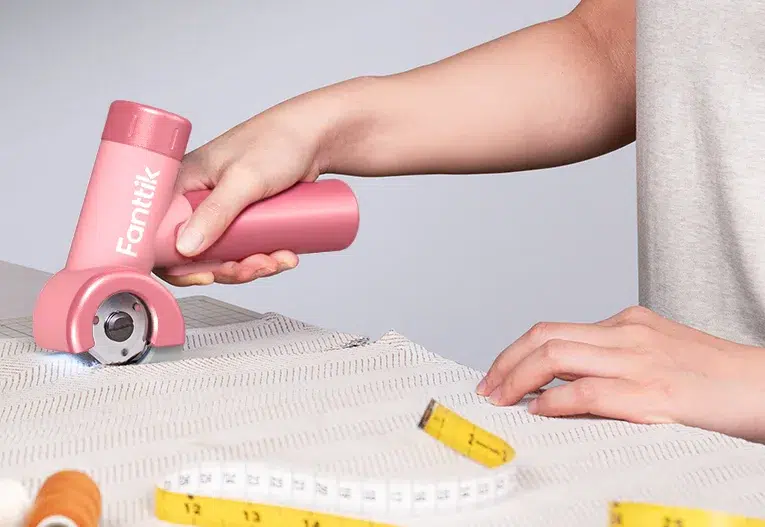 Person cutting fabric with electric cutter tool