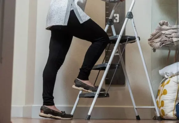 Person standing on a step ladder indoors.