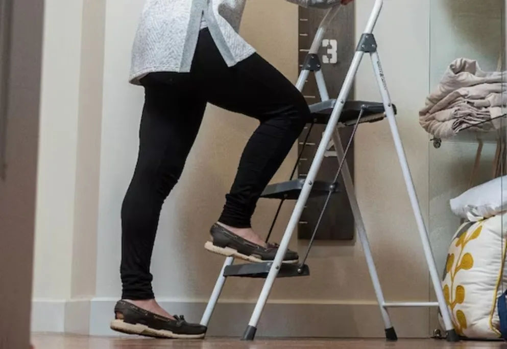 Person standing on a step ladder indoors.