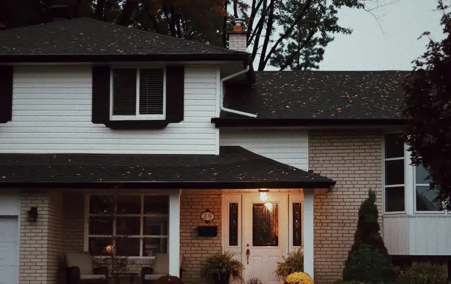 Two-story house with porch light on at dusk.