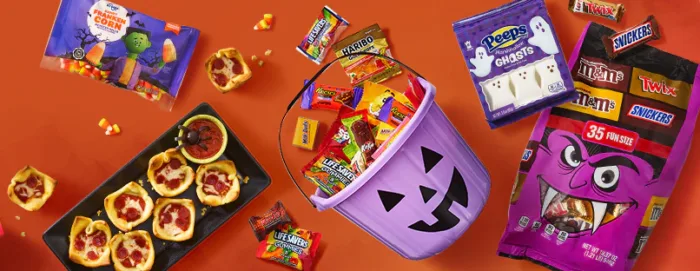 Halloween candy and treats spread on orange background.