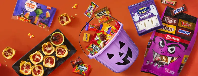 Halloween candy and treats spread on orange background.