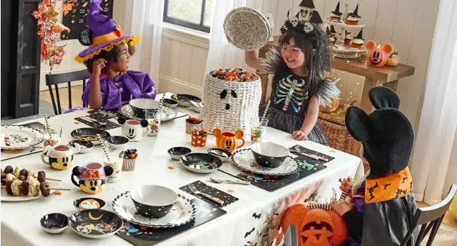 Kids in costumes enjoying Halloween party at table.
