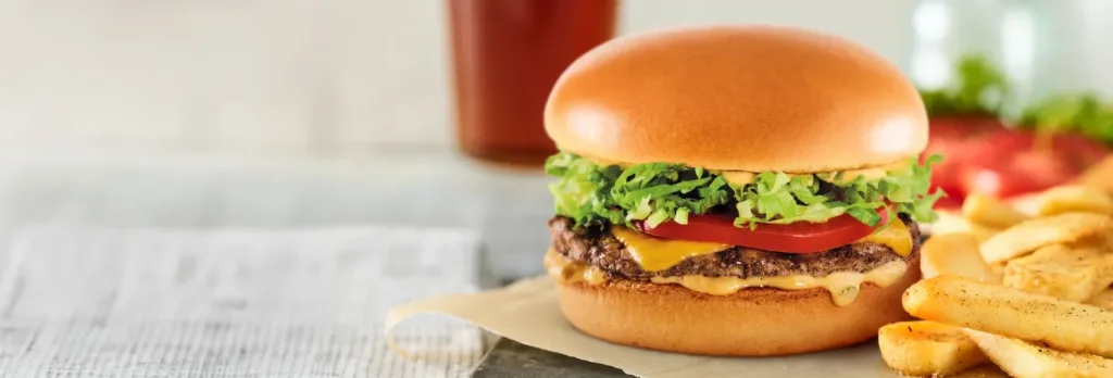 Cheeseburger with lettuce, tomato, fries on side.