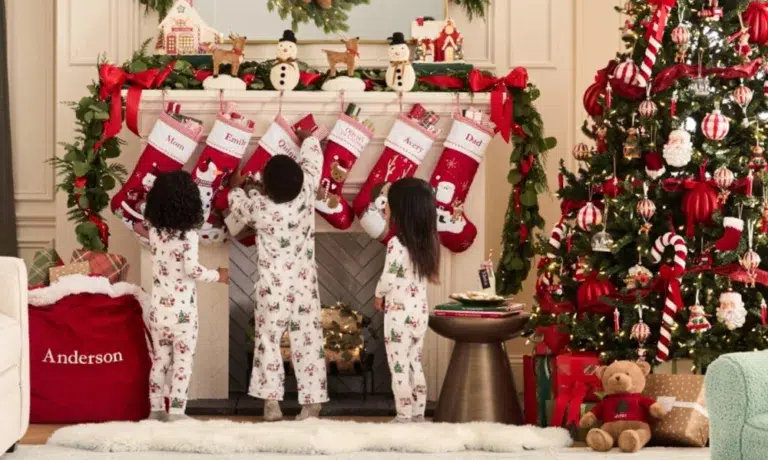 Children hanging Christmas stockings, decorated tree nearby.