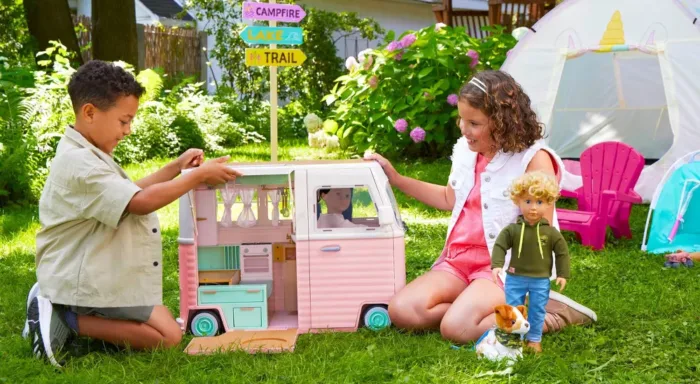 Children playing with toy camper in backyard.
