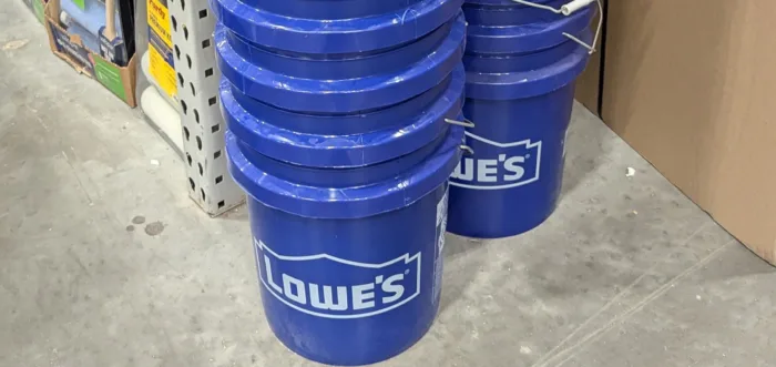Stack of Lowe's blue buckets in store aisle.
