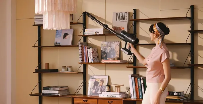 Woman cleaning bookshelf with handheld vacuum