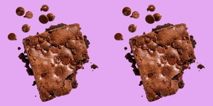 Two chocolate brownies with chips on purple background.